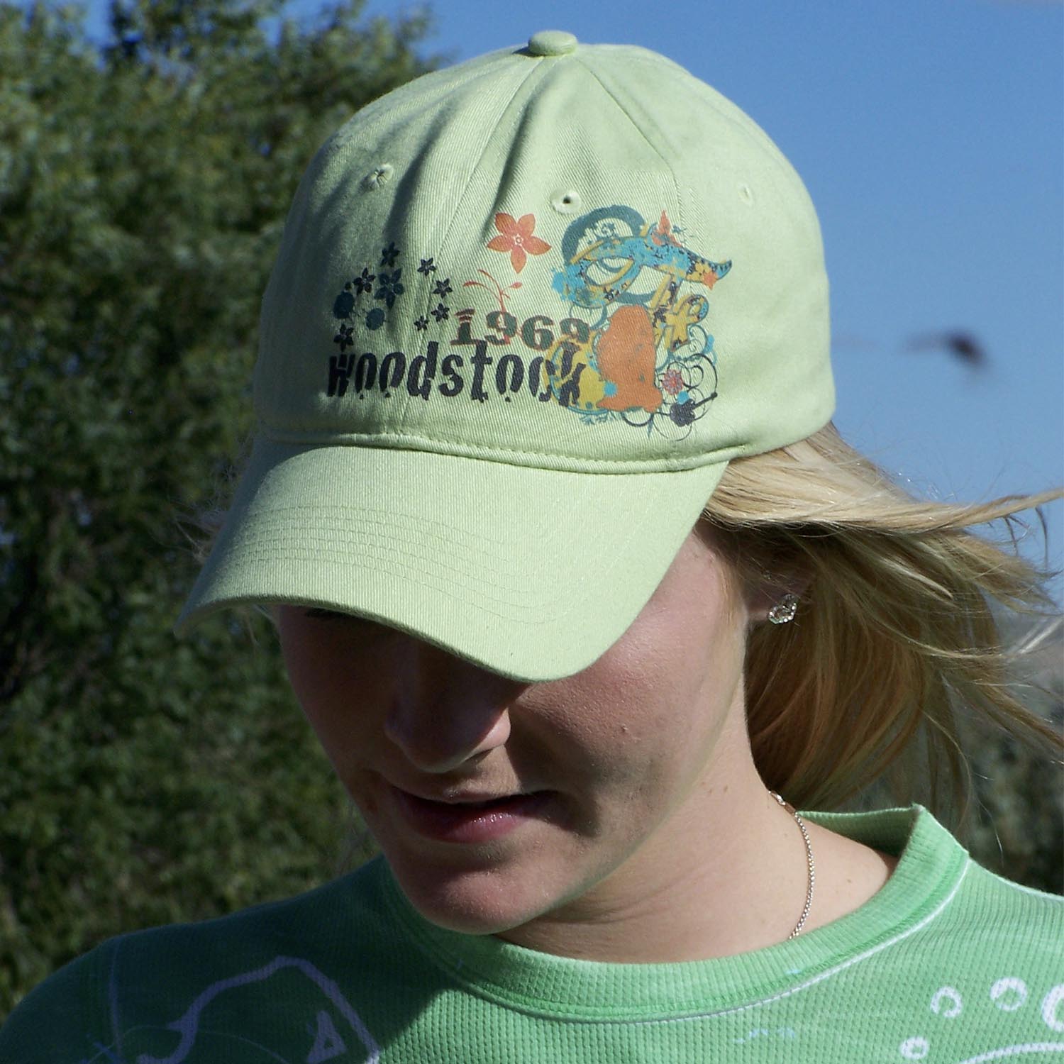 A person wearing a lime green cap with '1969 Woodstock' printed on the front.